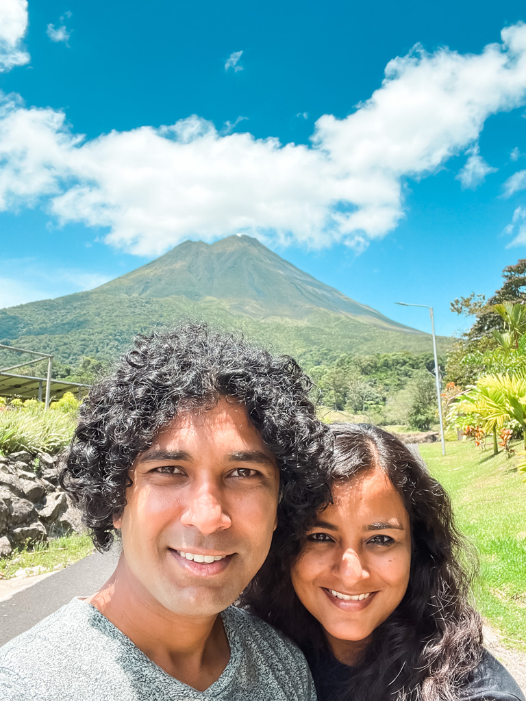 A man and woman with the Arenal Volcano in the background.