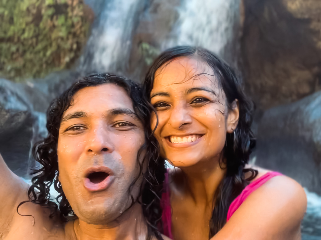 Selfie of a couple with big smiles at a hot spring waterfall in El Salvador.