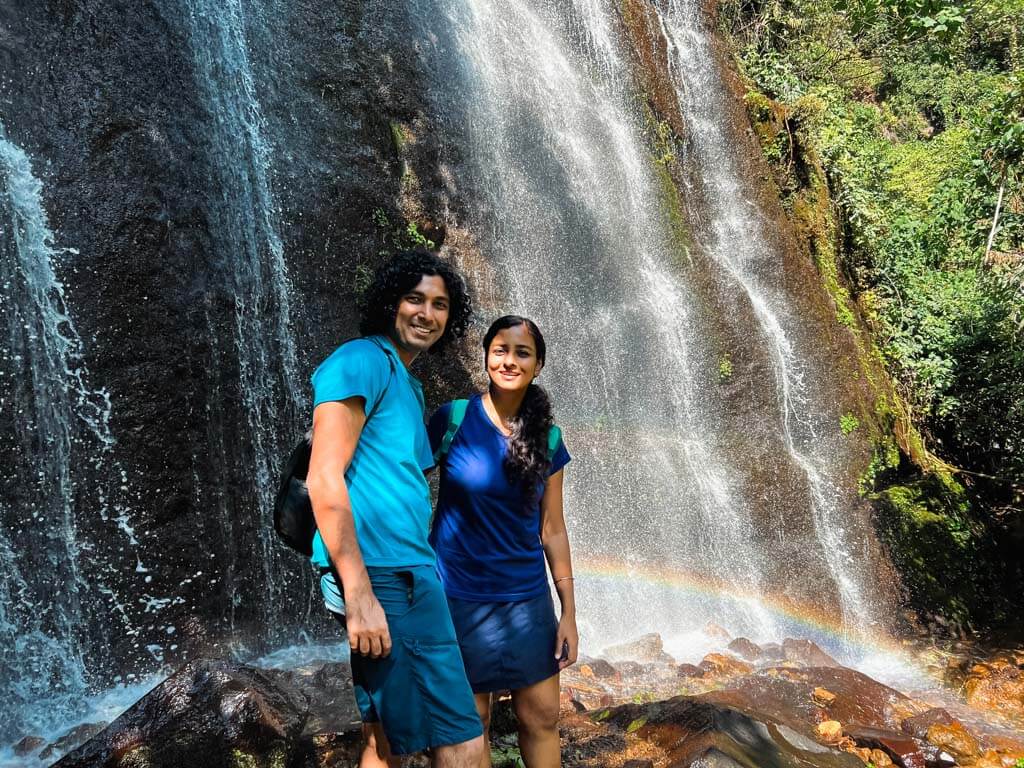 A couple at a waterfall of 7 cascadas in El Salvador. Rainbow in the waterfall.