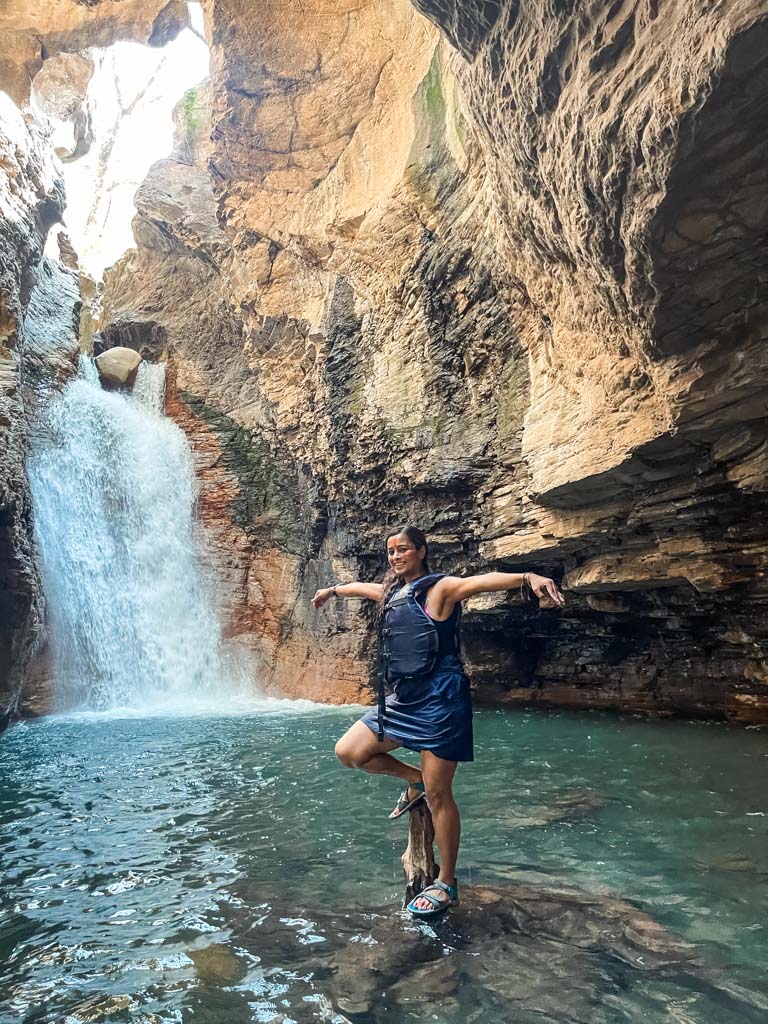 Woman balancing herself on logs at the natural pool of Catarata La Leona.