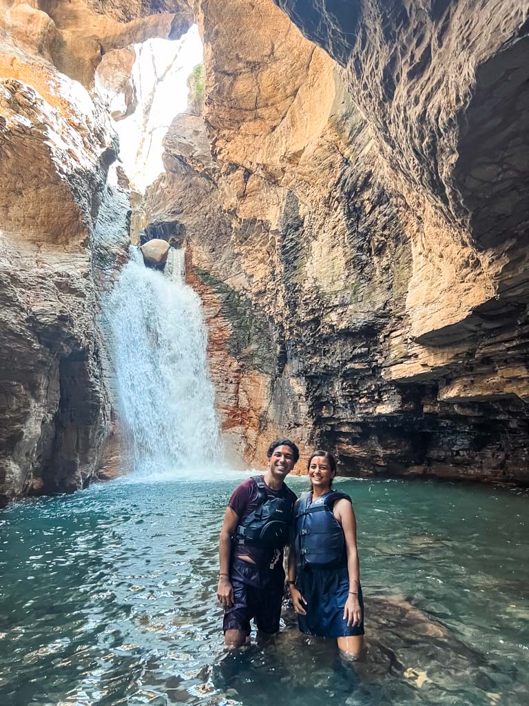 A couple standing inside the natural pool at La Leona waterfall.