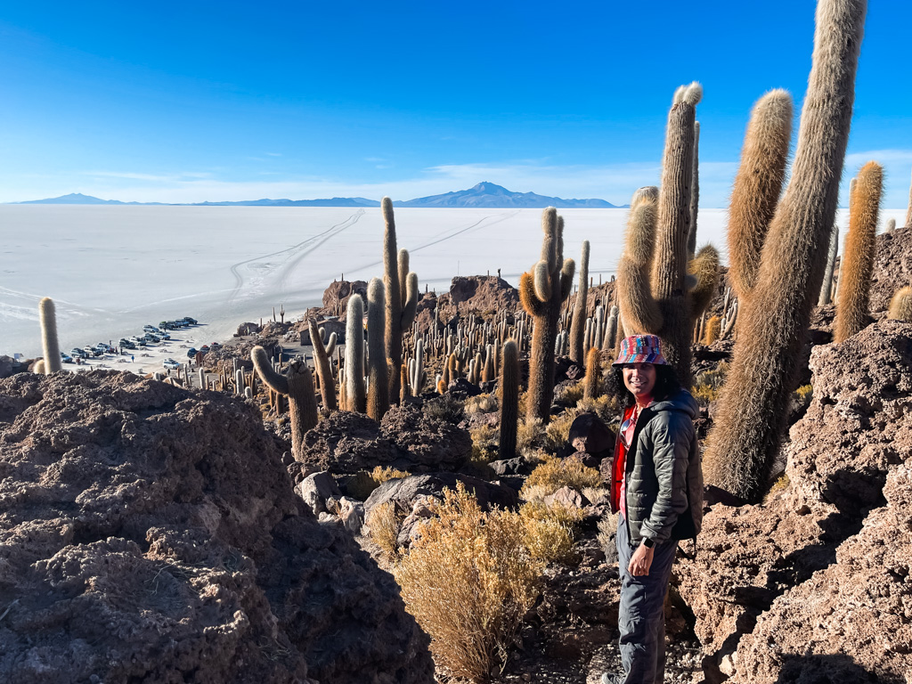 A man, looking small next to the giant cactus trees on Incahuasi Island in Bolivia.