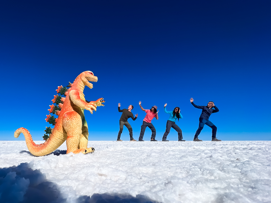 Perspective group photo with dinosaur on the salt flats of Bolivia.