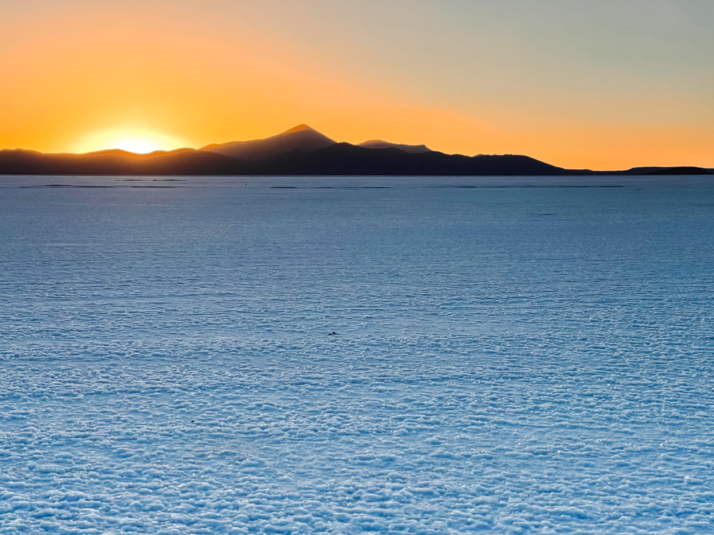 Orange shades on the sky during sunset hour on the salt flats of Bolivia. One of the best things to do in Uyuni.