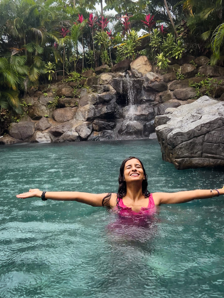 A woman enjoying the rains from a hot spring in La Fortuna, Costa Rica.
