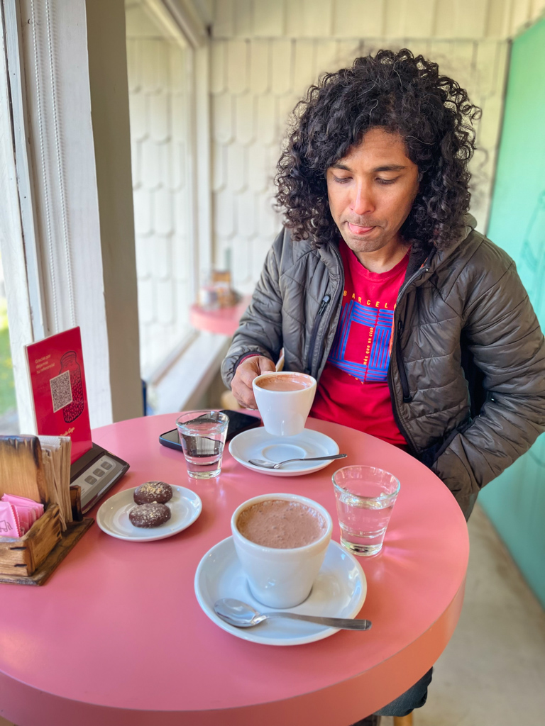 A man holding a cup of hot chocolate in a cafe in Bariloche, Argentina.