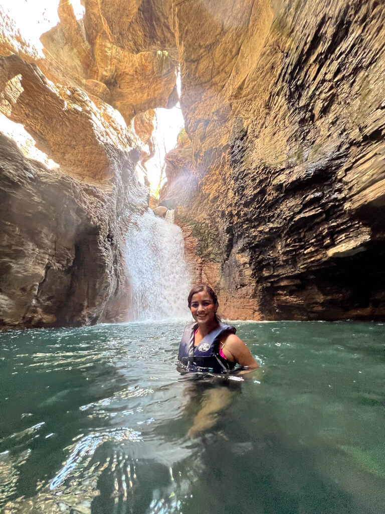 A woman in front of the La Leona Waterfall in Guanacaste, Costa Rica.