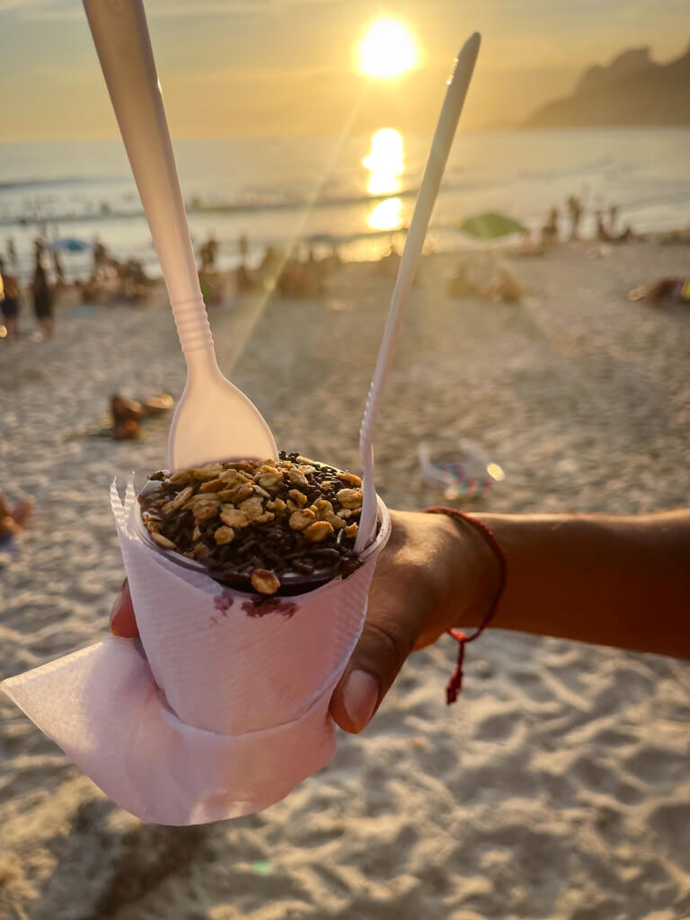 A cup of Açai with beach sunset in the background.