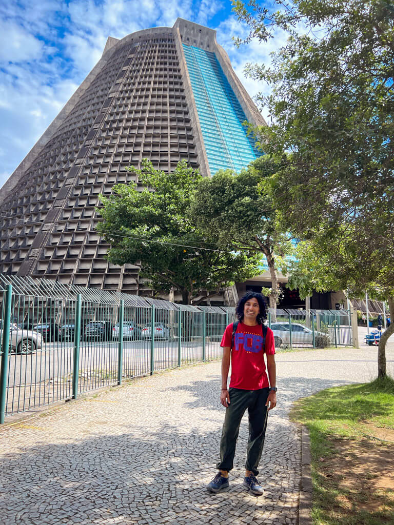 Man standing next to the Metropolitan Cathedral of Rio de Janeiro.