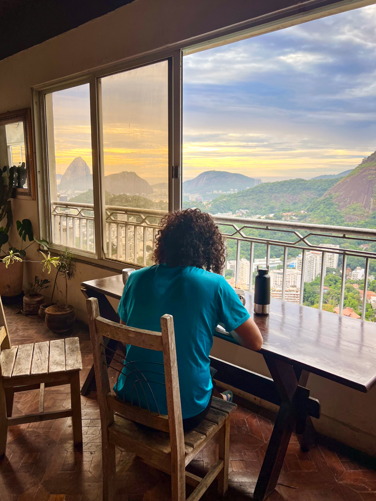 View from the window from a house in Santa Teresa, Rio de Janeiro. Man seated at a desk by the window.