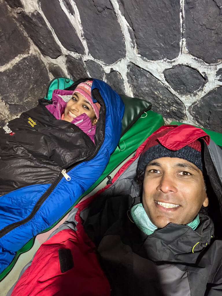 A man and a woman inside their sleeping bags inside their Salkantay Trek camp stay, posing for a selfie.