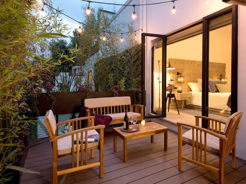 A patio with outdoor chairs and tables with wine bottle and glasses with a candle lit in the evening, at the H21 Hospedaje Boutique Hotel in Coyoacan, if you are wondering where to stay in Mexico City, this is one of our favorite areas.