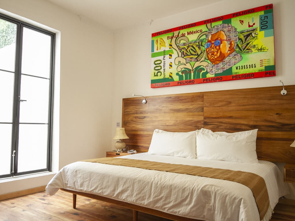 A bedroom with a colorful art on a currency note at NaNa Vida CDMX in Mexico City.