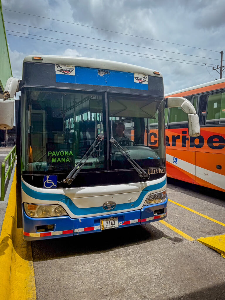 Pavona-bound bus standing next to the orange bus at the terminal in Cariari.