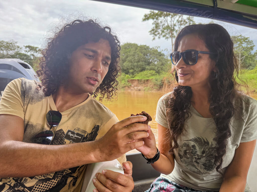 A man and a woman holding together a small cupcake, on the boat from Pavona to Tortuguero.