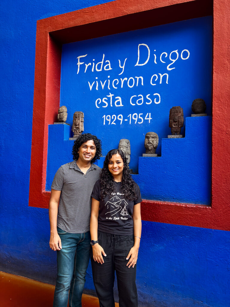 A man and a woman posing for a photo at the Frida Kahlo Museum. The writing on the wall says "“Frida and Diego lived here”. Frida Kahlo Museum is a must visit when exploring Coyoacan in 2-3 days or even 1 day.