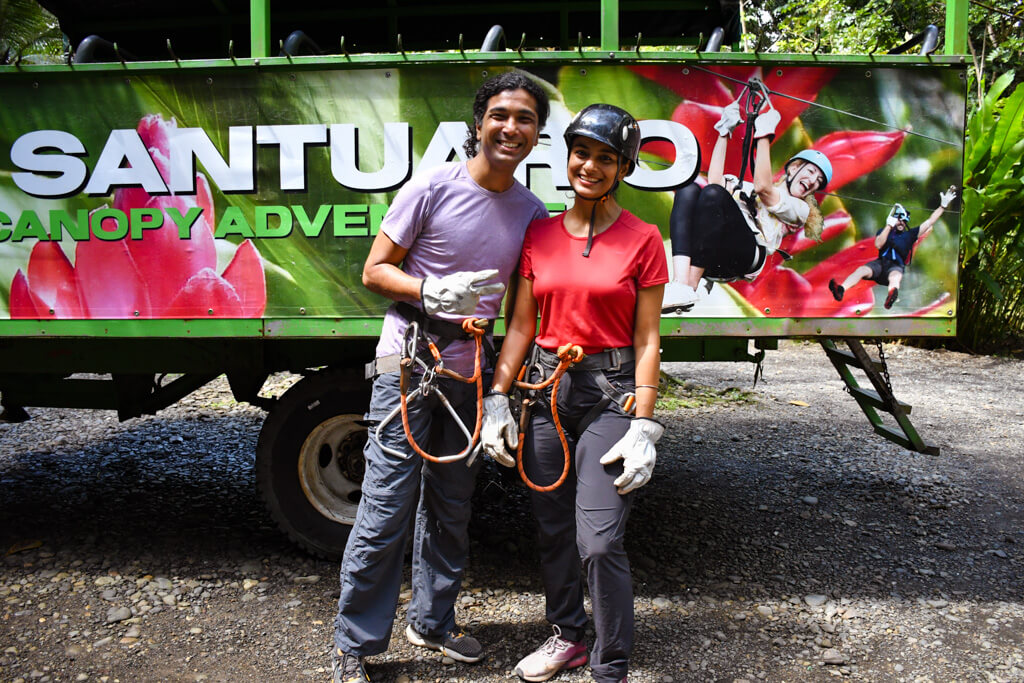 A man and a woman, each of them geared up with harness and helmet, ready for ziplining in Manuel Antonio.