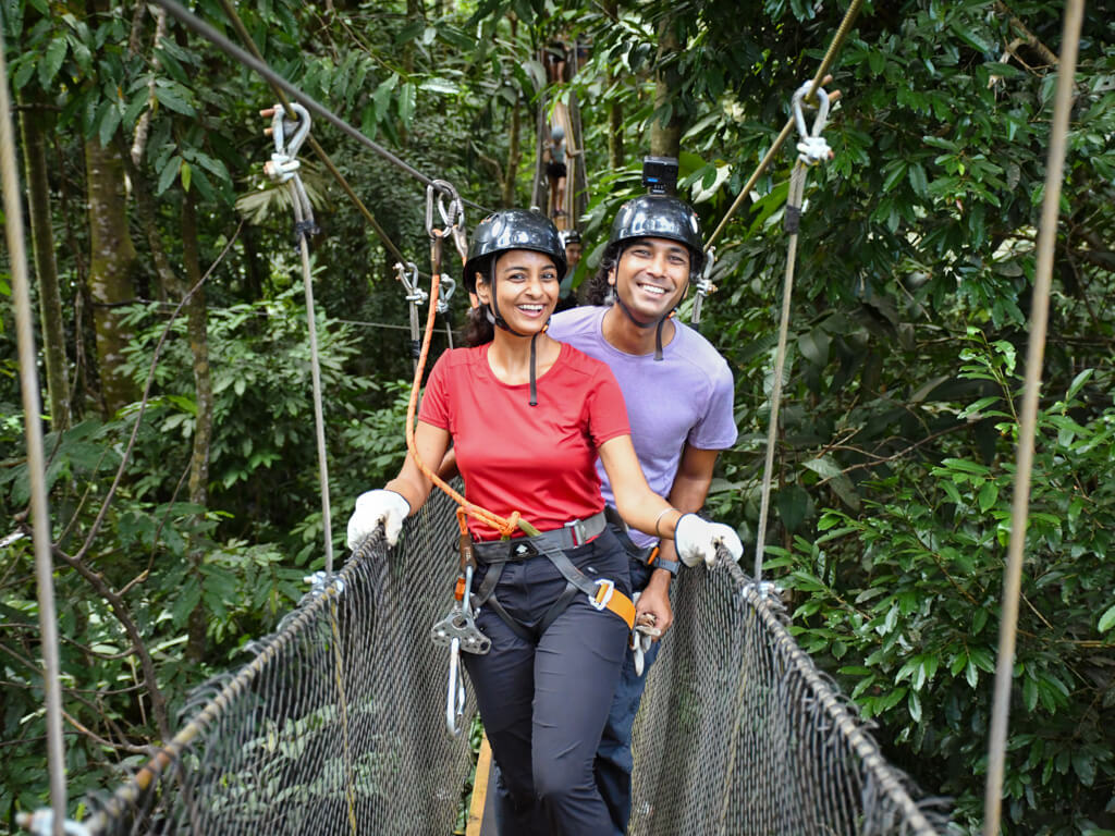 A man and a woman posing for a photo standing on a hanging bridge, part of El Santuario Canopy Tour in Manuel Antonio, Costa Rica.