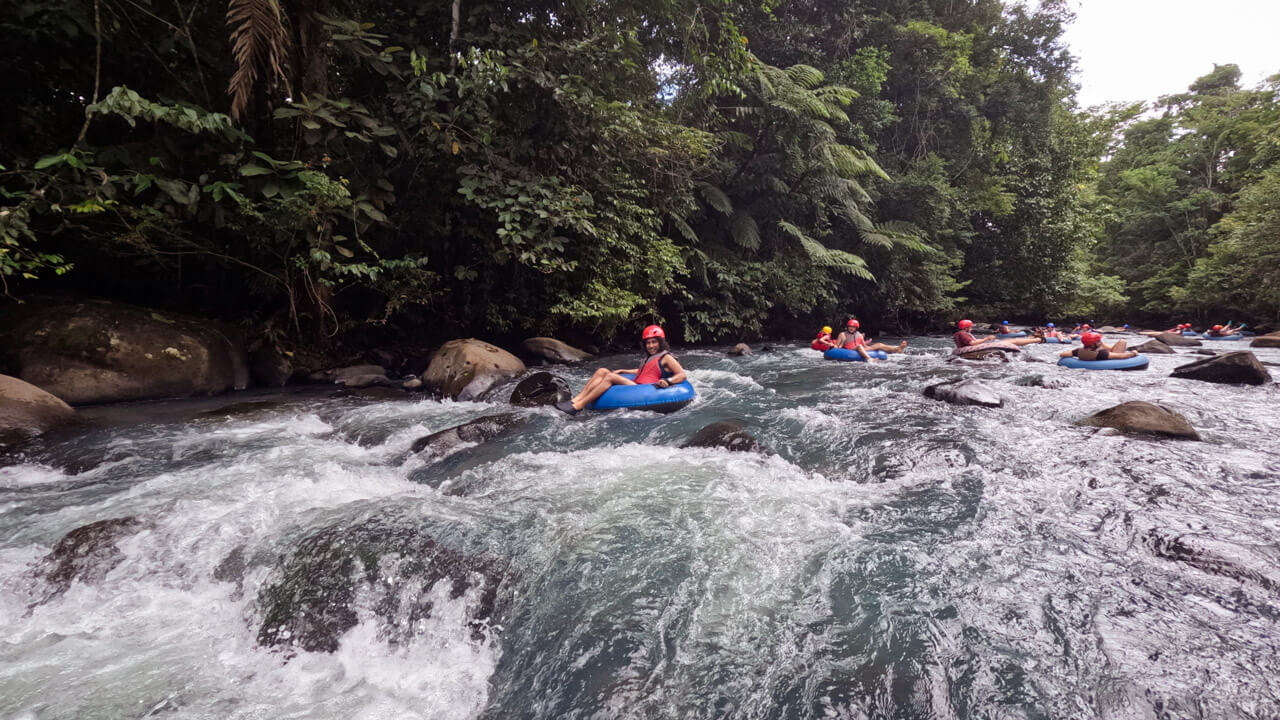 Rio Celeste Tubing Tour in Costa Rica. A few people tubing down the rapids of Rio Celeste.