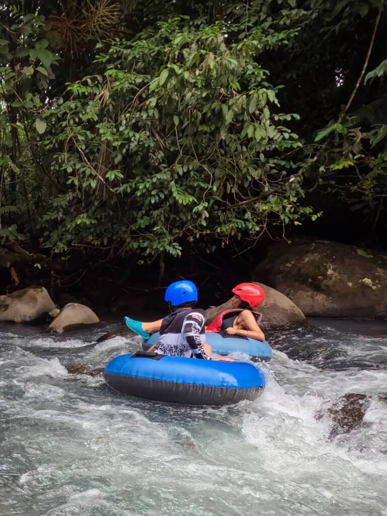 One of the guides helping a woman to navigate the rocks and the rapid while tubing on Rio Celeste.