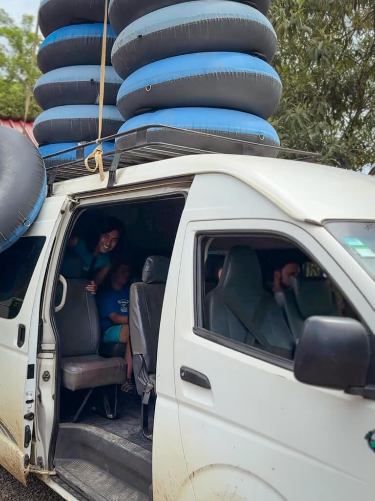 A white minivan with river tubes stacked on top of the vehicle.