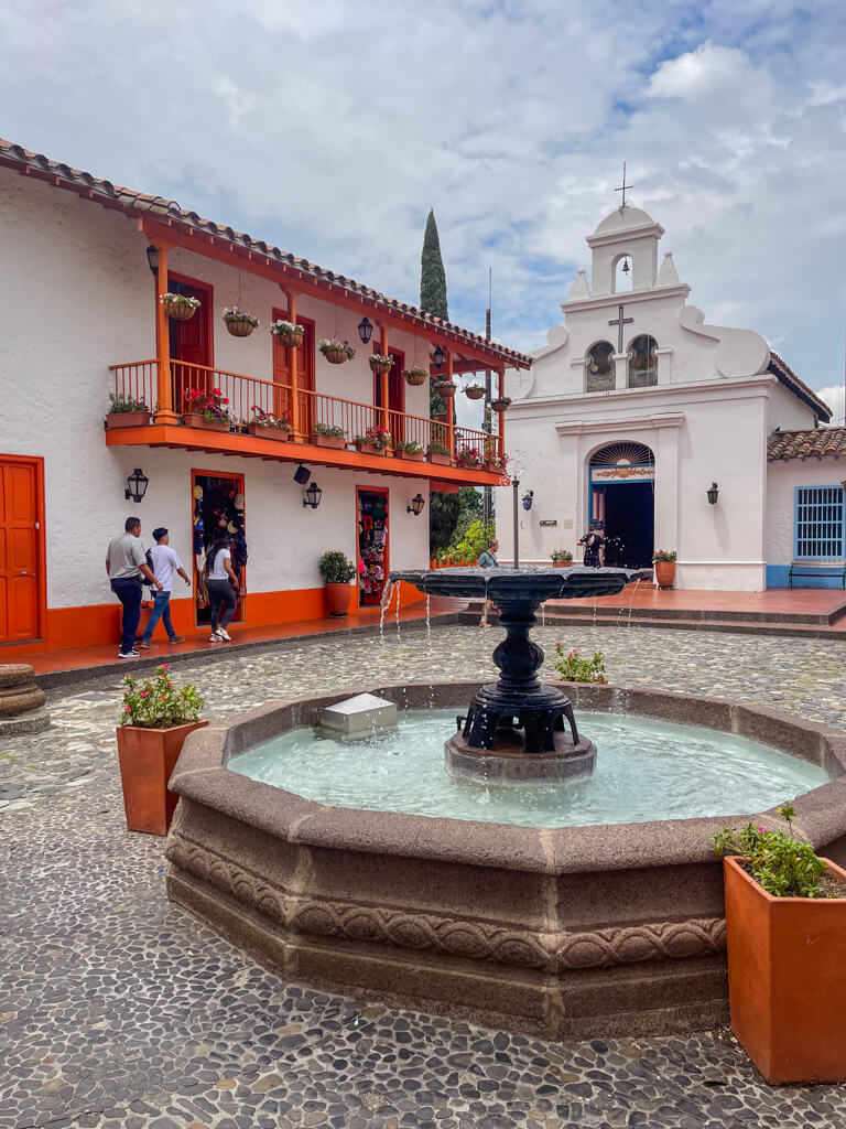 A fountain, colorful buildings and a Church at Pueblito Paisa in Medellin.