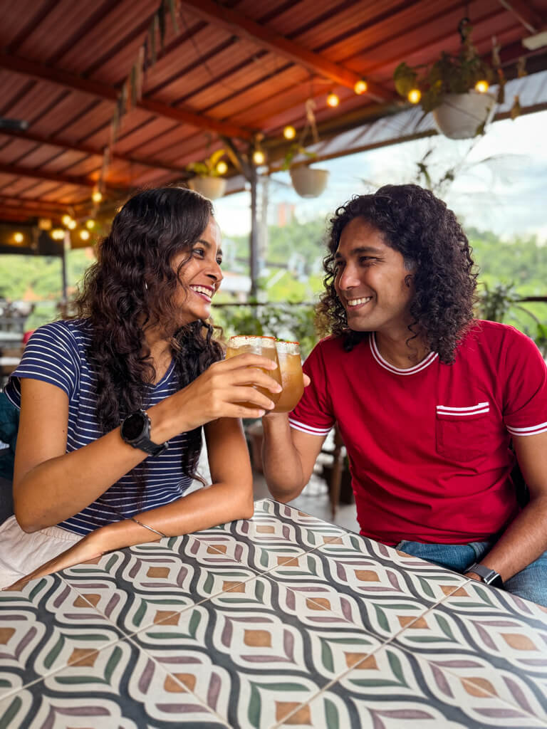 A man and a woman doing cheers with their glasses of Tamarindo Sodas, on a Local Food Tour in Medellin.