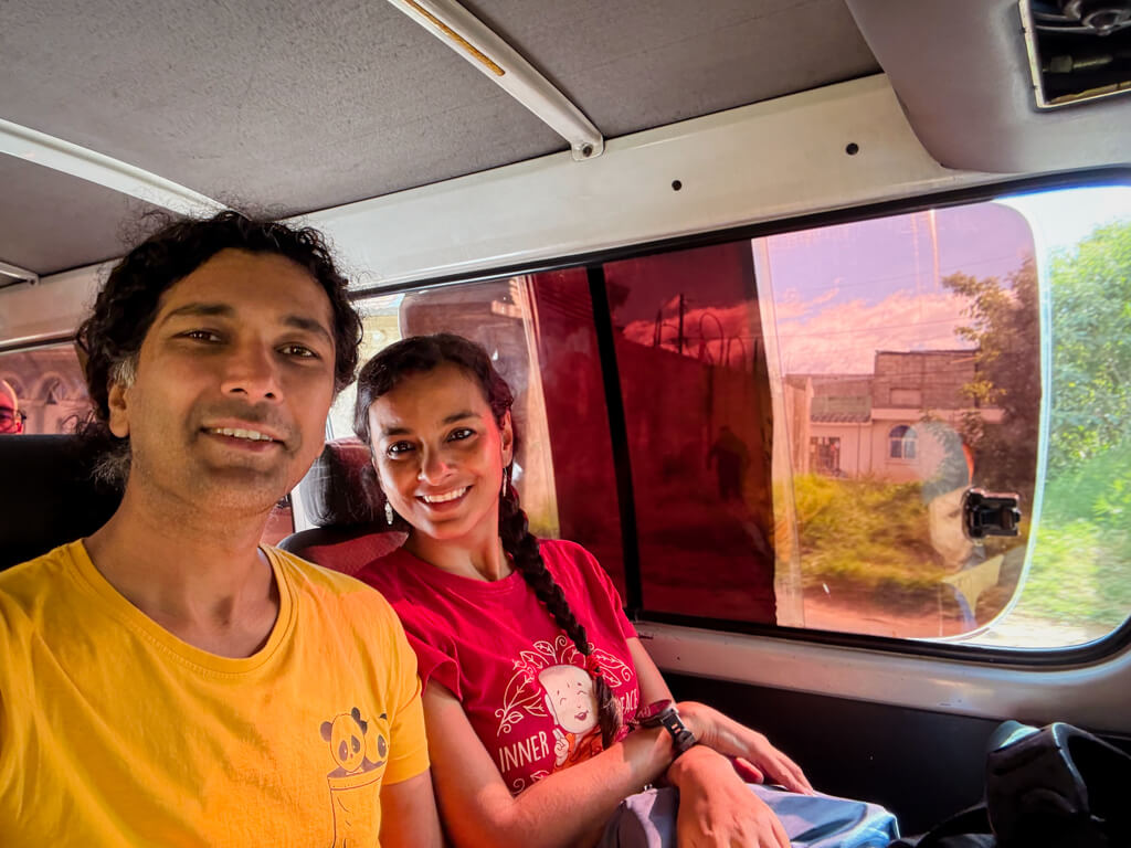 A man in yellow t-shirt and a woman in red t-shirt on the way from Guatemala City Airport to Antigua Guatemala, seated in a shared shuttle booked from the airport counter.