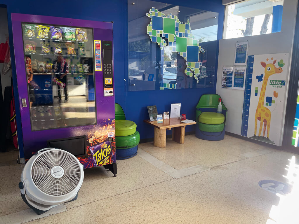Inside Adobe Rent A Car Liberia Airport Office. Seating, snacks vending machine.