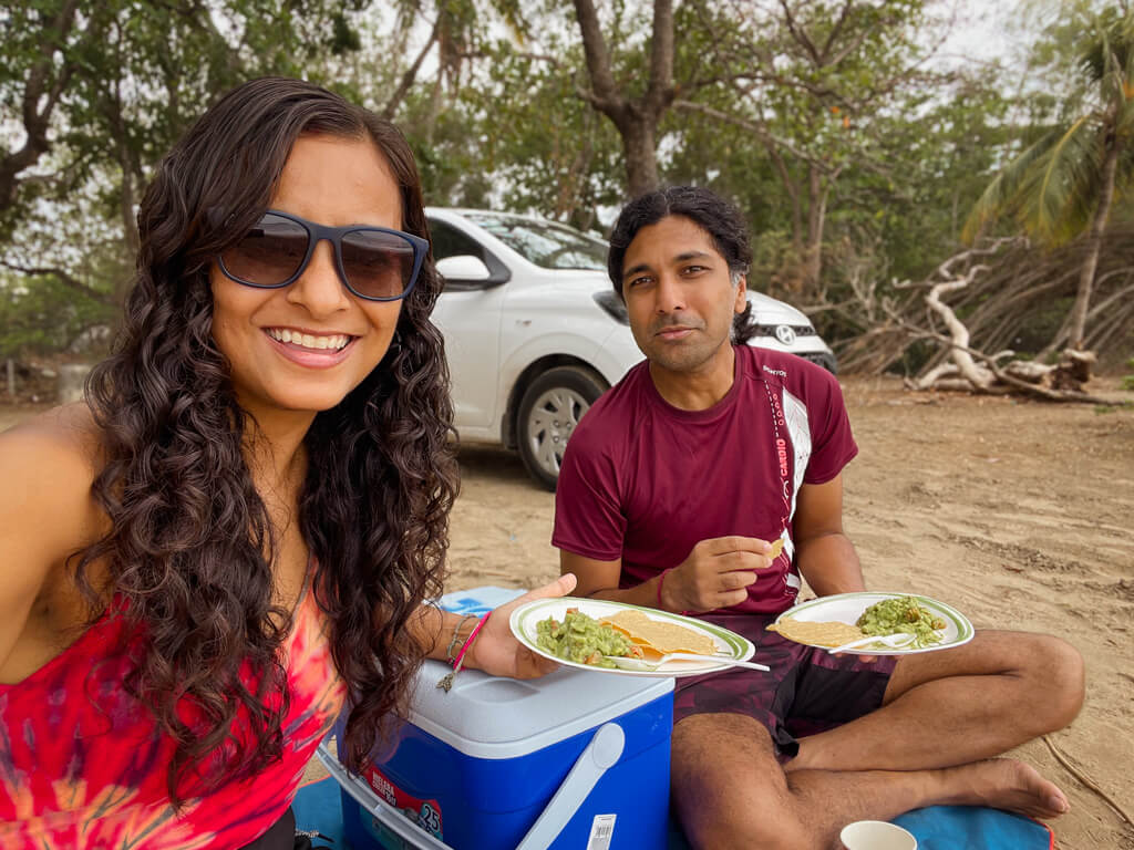 A woman and a man enjoying a beach picnic in Costa Rica. Adobe's rental car parked in the background.