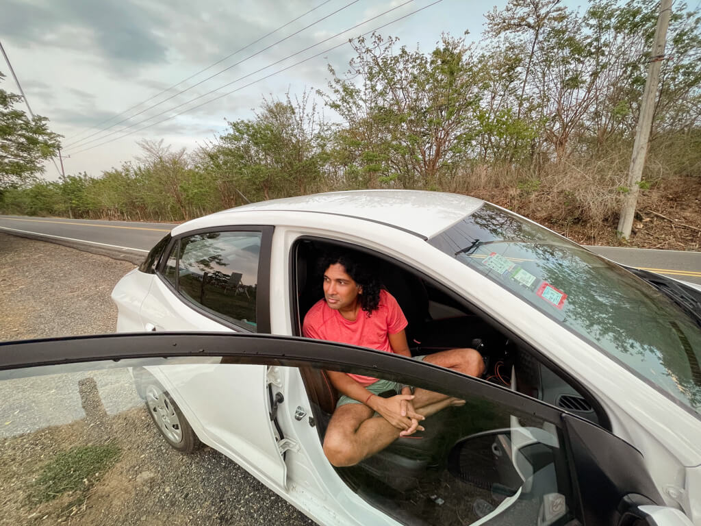 A man seated inside Adobe's rental car, a white colored Hyundai Grand i10.
