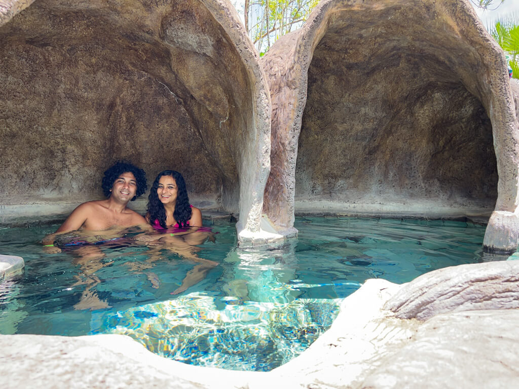 A man and a woman, in one of the cozy corners in a cave like spot at a hot spring pool at Los Lagos Hotel.