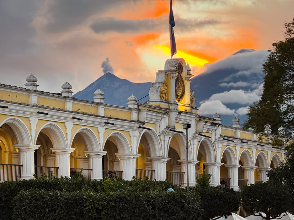 Royal Palace of the Captains General with Acatenango and Fuego volcanoes in the backdrop, during sunset hour in Antigua Guatemala.