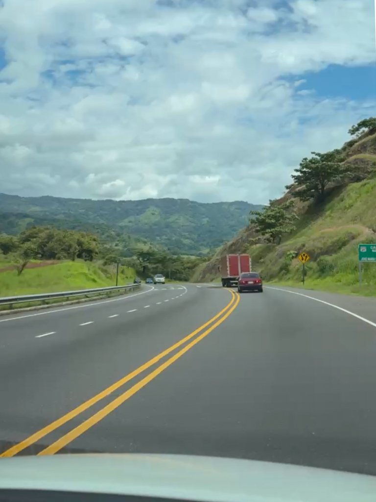 Cars on a highway in Costa Rica with views of the green hills around.